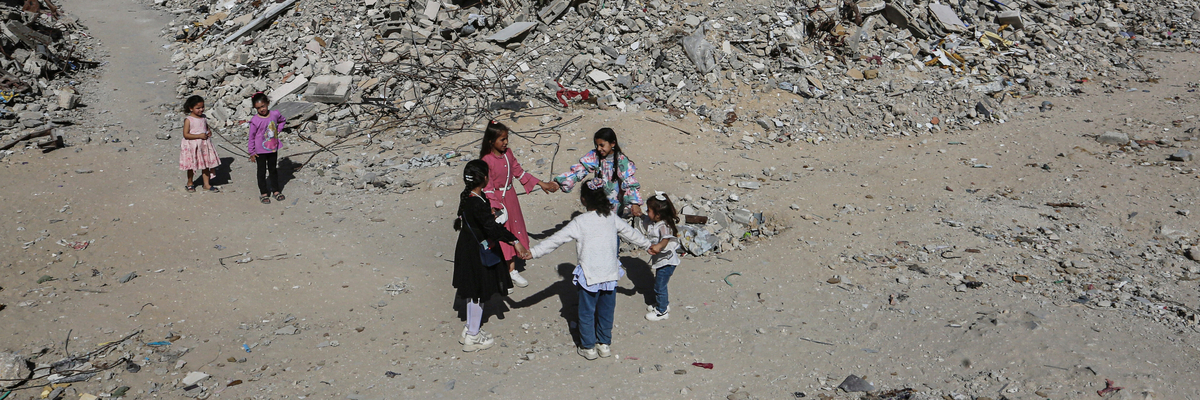Mädchen tanzen Hand in Hand inmitten der Trümmer von Gebäuden und provisorischen Zelten