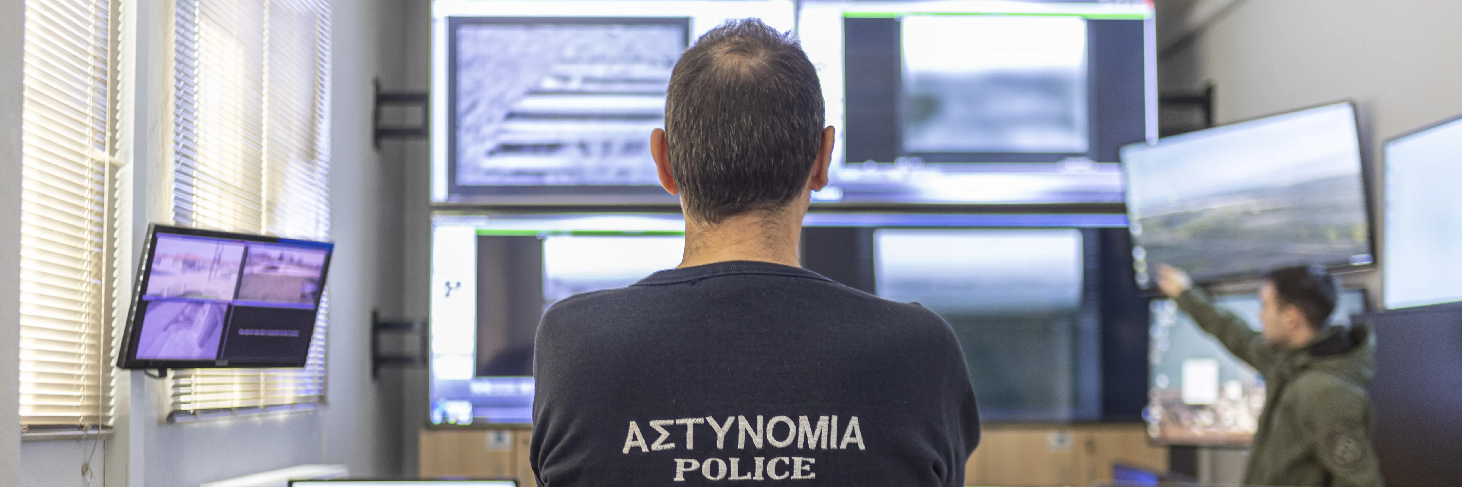Polizist steht vor Überwachungsmonitoren