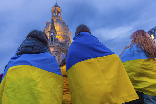 Mehrere Personen mit ukrainischen Flaggen stehen vor Frauenkirche in Dresden