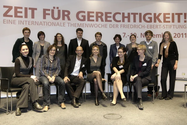 Das Team der Themenwoche "Zeit für Gerechtigkeit" der Friedrich-Ebert-Stiftung stehend und sitzend vor der Podiumsrückwand der Veranstaltung.