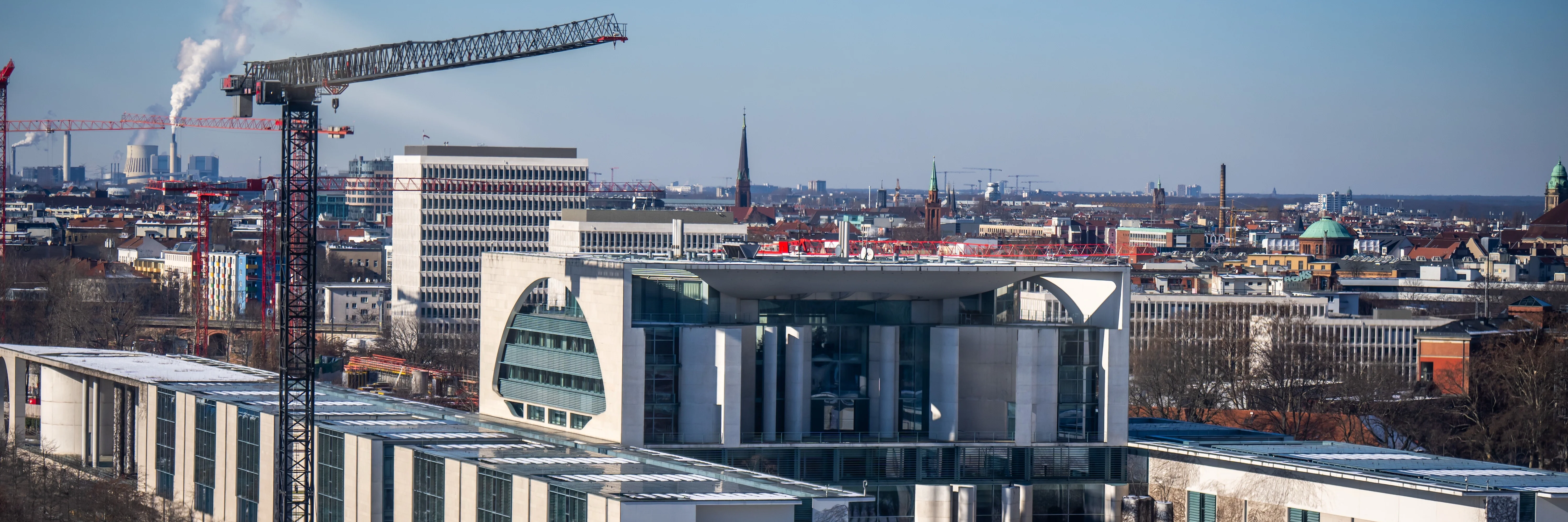 Sicht auf das Bundeskanzleramt in Berlin im Winter mit einem Baukran daneben.