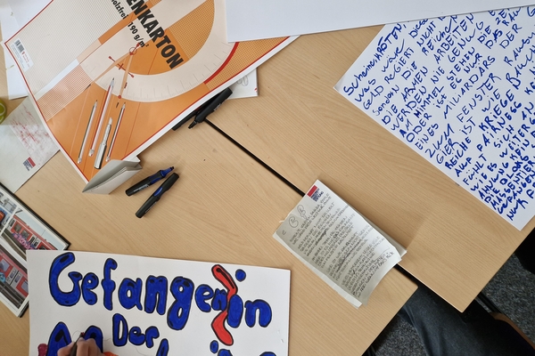 Draufsicht auf einen Schreibtisch, auf dem verschiedene beschriebene Papiere, Materialien und Textmarker liegen. 