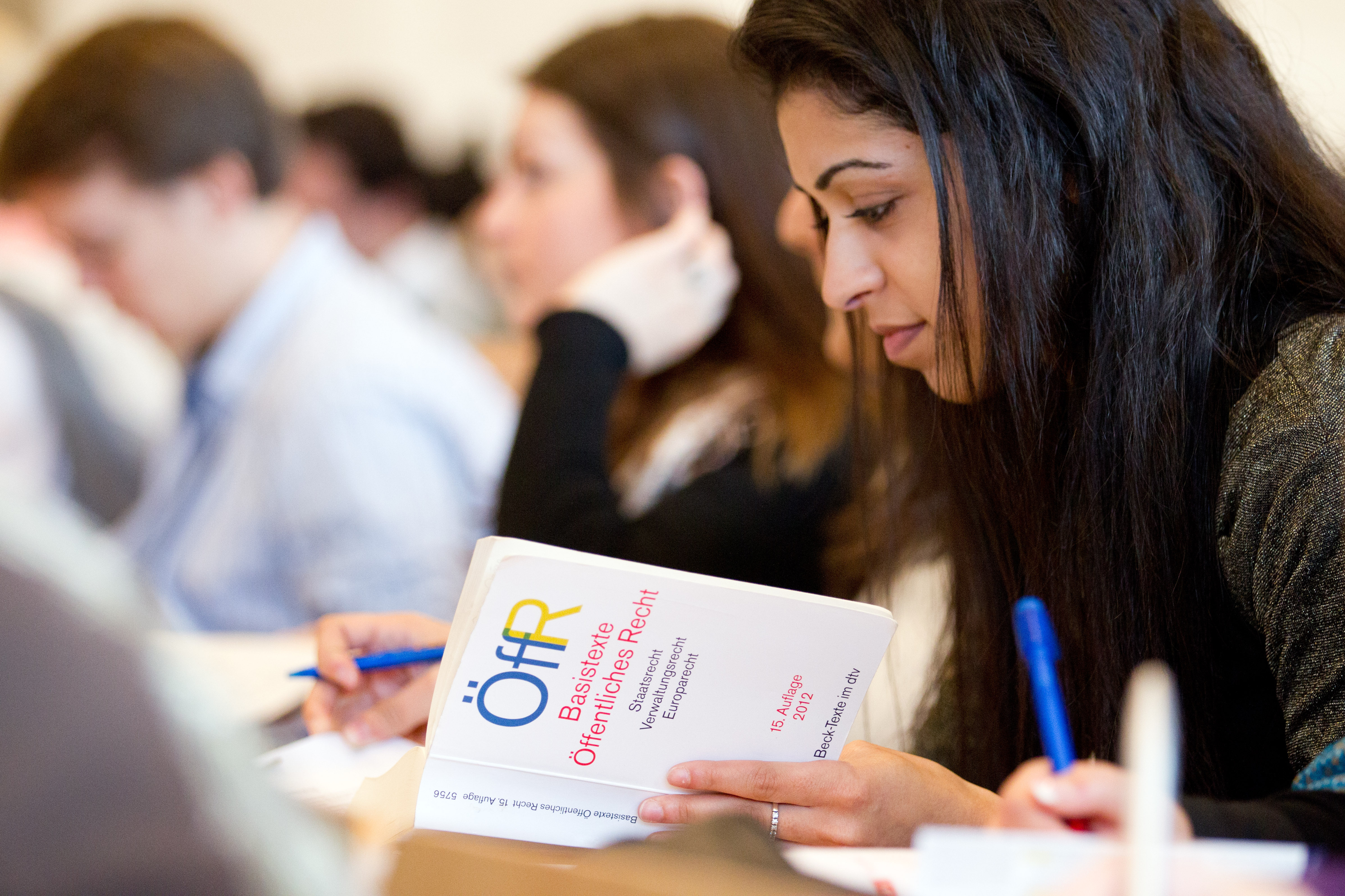 Eine Jurastudentin sitzt in der Bibliothek und liest in Fachliteratur.