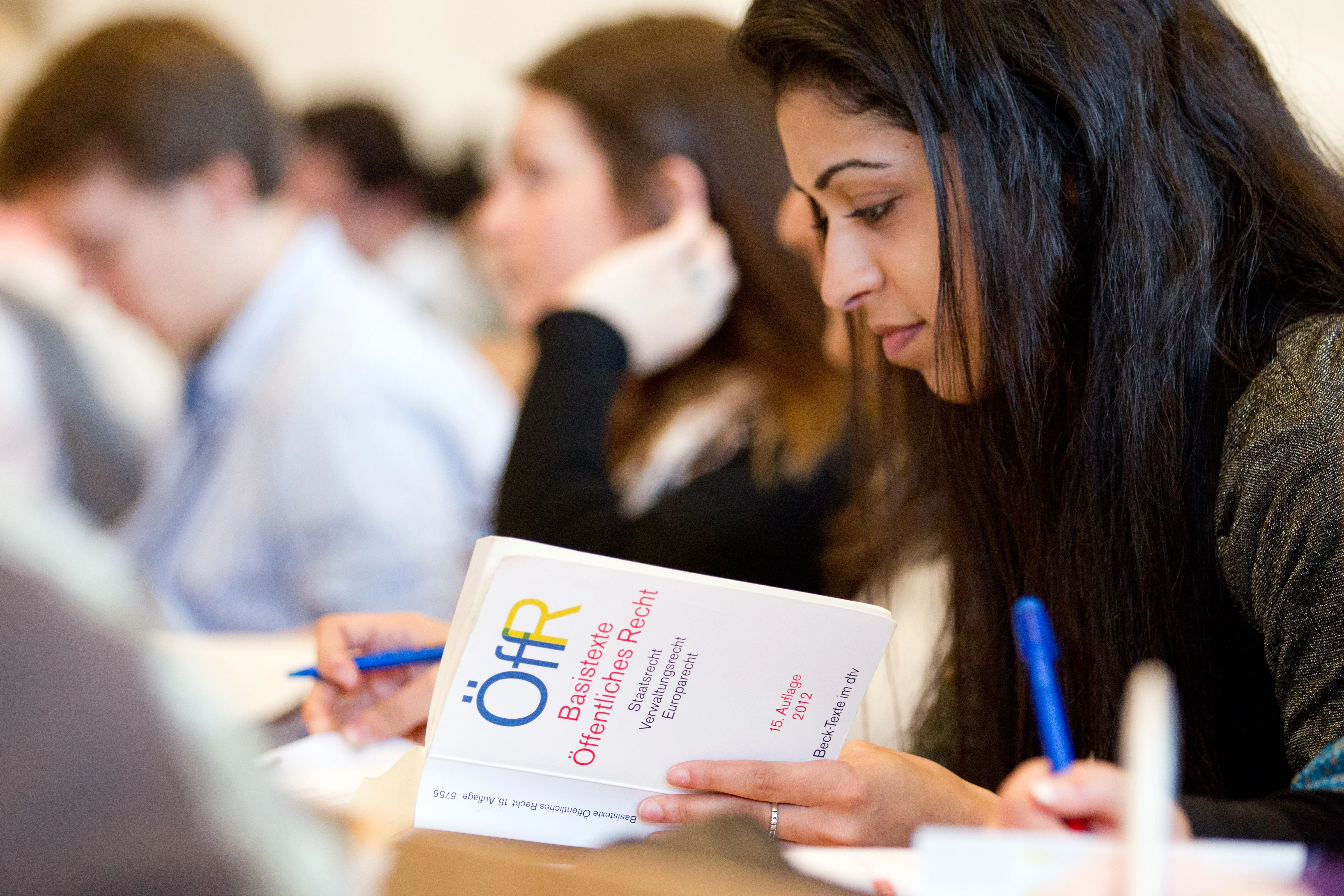 Eine Jurastudentin sitzt in der Bibliothek und liest in Fachliteratur.