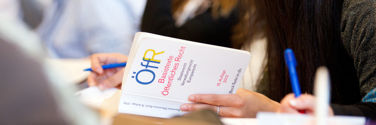 Eine Jurastudentin sitzt in der Bibliothek und liest in Fachliteratur.