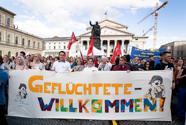 Protesters hold a banner reading ‘Refugees welcome!’