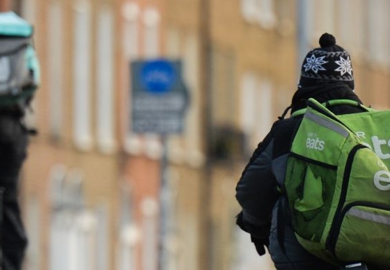 Zwei Essenslieferanten auf Fahrrädern von hinten.