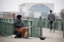 Ein Obdachloser sitzt in Berlin an der Spree im Regierungsviertel und bittet um Unterstützung.