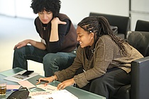 Zwei junge Frauen füllen lachend Moderationskarten in einem Workshop aus.