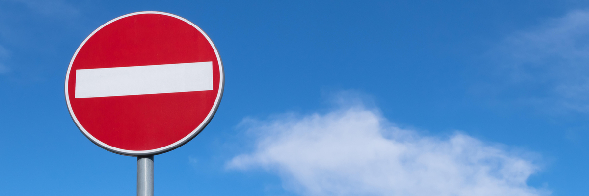 rotes Verkehrsschild mit weißem Balken: Einfahrt verboten, vor blauem Himmel mit weißen Wolken