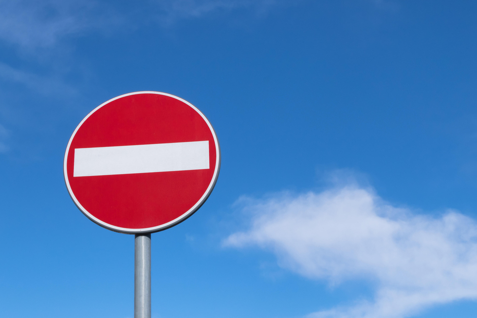 rotes Verkehrsschild mit weißem Balken: Einfahrt verboten, vor blauem Himmel mit weißen Wolken