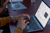 Foto einer Person, die an einem Laptop einen Text schreibt.