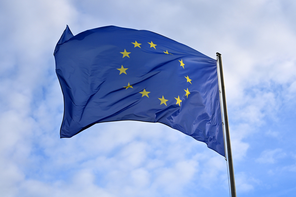 Europäische Flagge flattert im Wind vor blauem Himmel