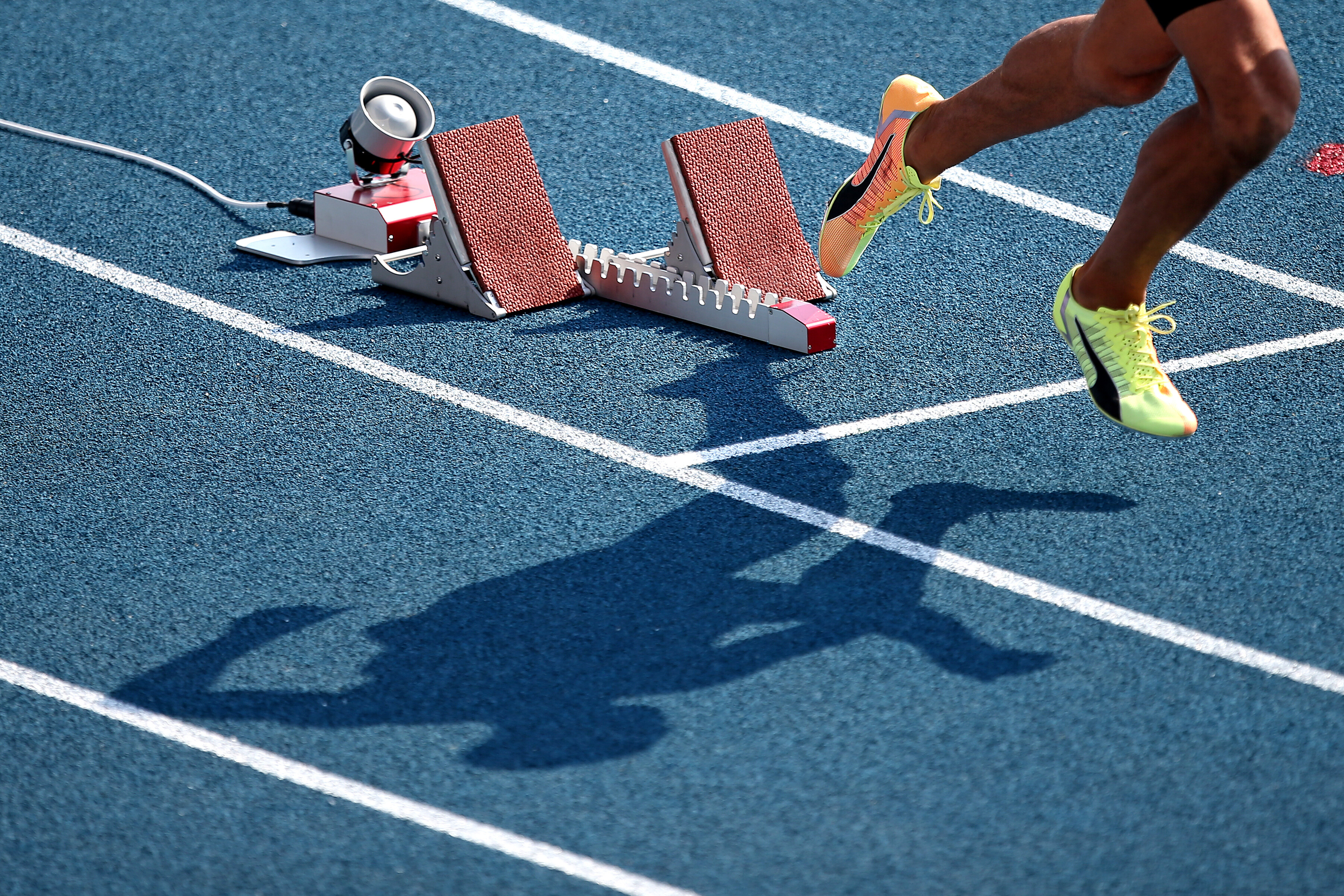 Foto: Startblock mit Beinen und Schatten eines Läufers 