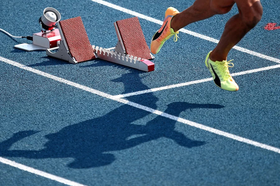 Foto: Startblock mit Beinen und Schatten eines Läufers 