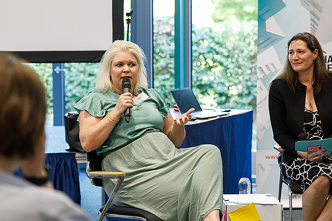 Fischbowl Diskussion. Eine Teilnehmerin im grünen Kleid redet zum Plenum.