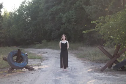 Iryna Pinchuk in a black evening dress in her home country of Ukraine next to border elements.