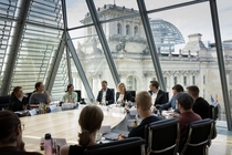 Die Teilnehmenden sitzen an einem Tisch im Bundestag und sind im Gespräch Nancy Faeser.