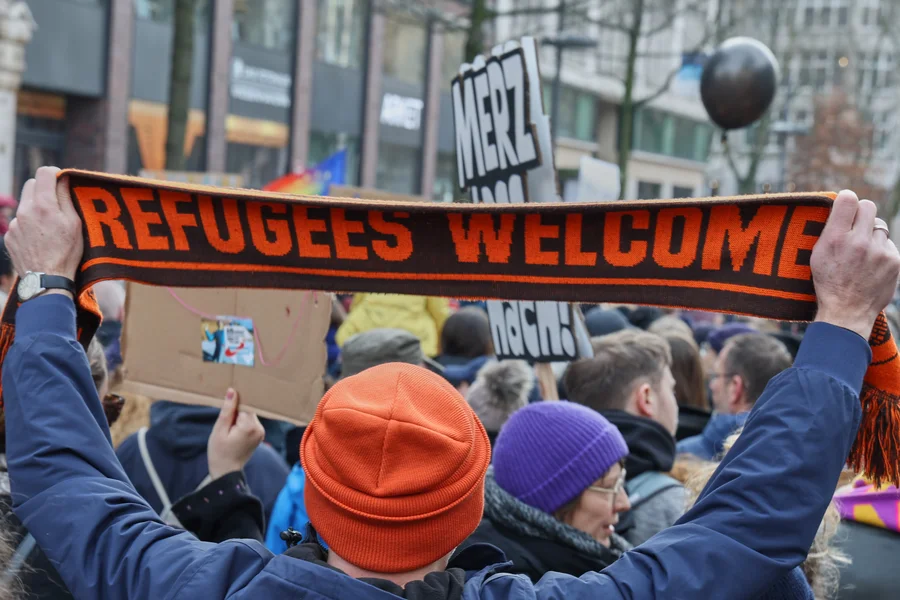 Ein Teilnehmer einer Demonstration hält einen Schal mit der Aufschrift „Refugees welcome".