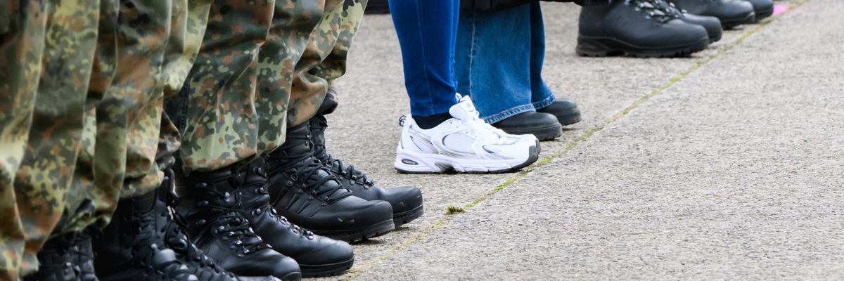 Eine Reihe Soldaten, daneben zwei Personen in zivil