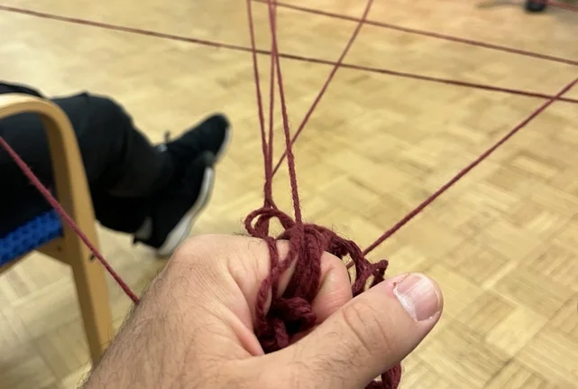 Ein Mann hält Fäden in der Hand, die ein Netz mit anderen Menschen bilden.