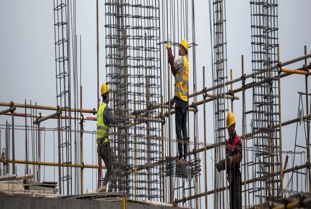 Three construction workers working on steel scaffolding