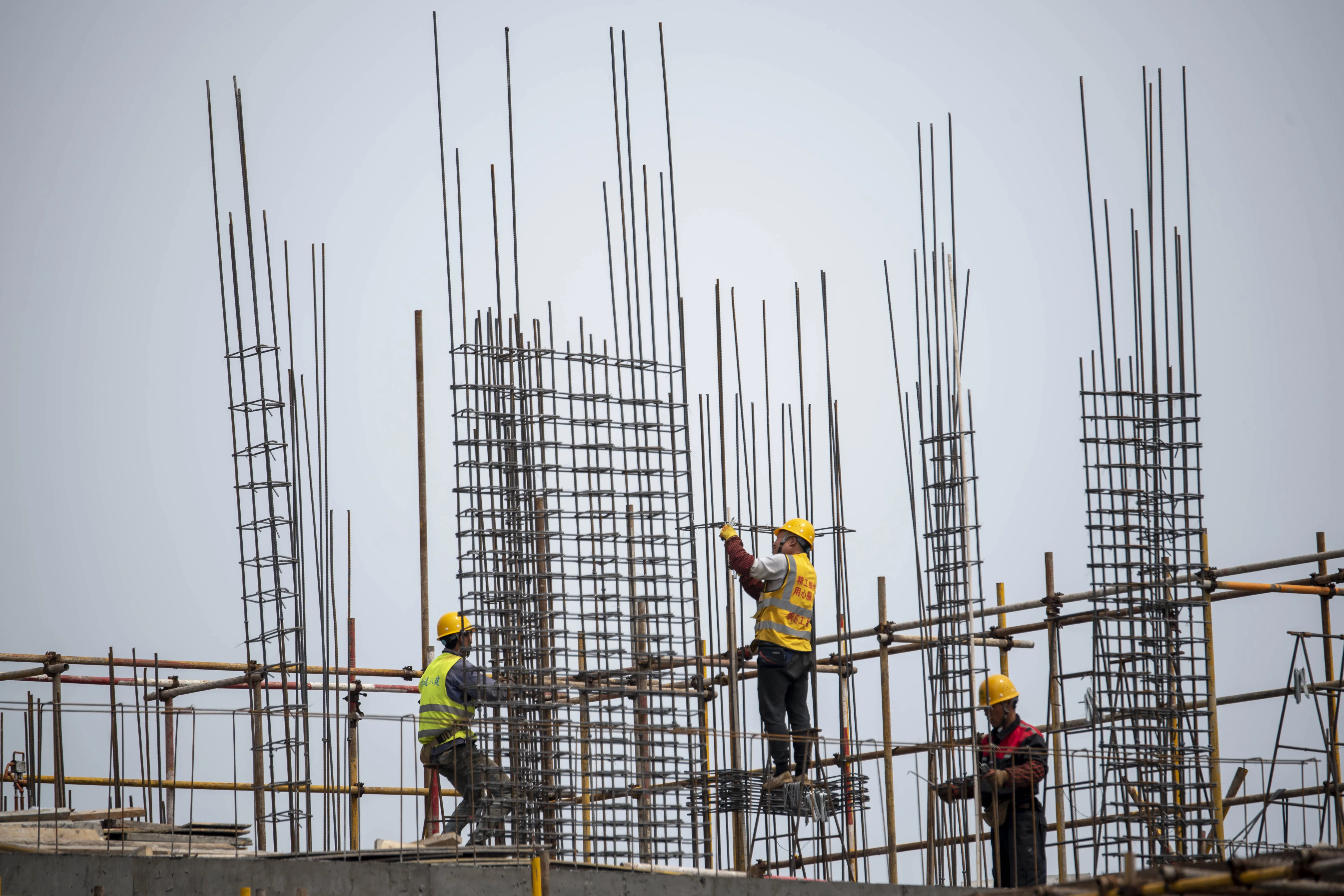 Drei Bauarbeiter arbeiten auf einem Stahlgerüst