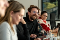 Ein Teilnehmender sitzt an einem Tisch und diskutiert mit der Gruppe.