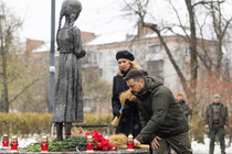 Wolodymyr Selenskyj und seine Frau beim Niederlegen von Weizenähren an der Statue "Bittere Erinnerung an die Kindheit", die ein abgemagertes junges Mädchen zeigt, darum Kerzen und Rosen