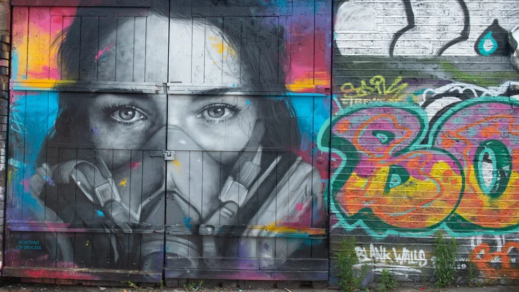 Das Graffiti des Straßenkünstlers Zabou zeigt eine junge Frau mit Maske.