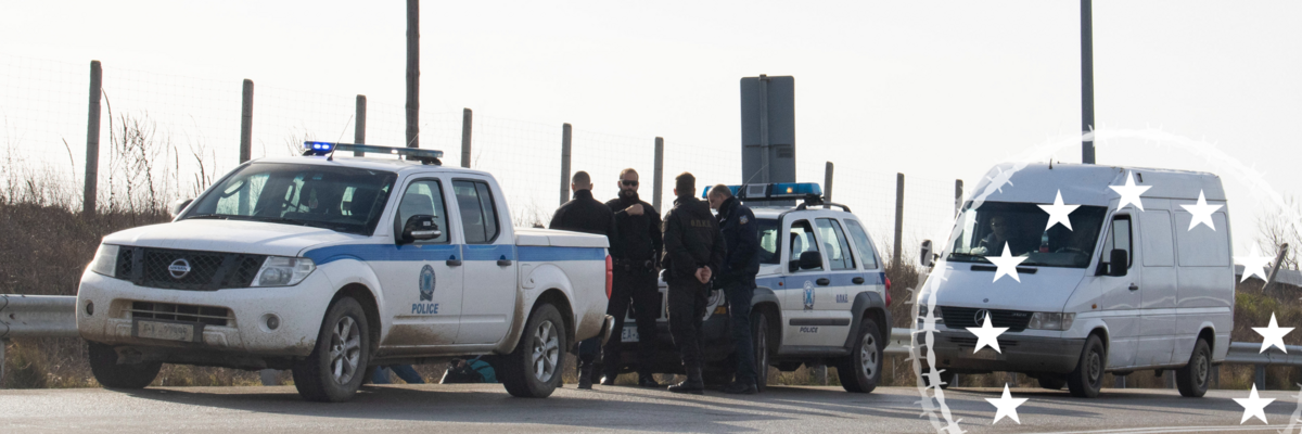 Zwei Grenzpolizeiwagen und Beamte an einer Grenze, dahinter ein weißer Transporter.