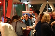 Foto von Teilnehmenden der MedienAkademie, die sich an Stehtischen unterhalten.