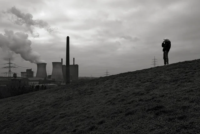 Ein Jugendlicher auf einem Hügel. im Hintergrund eine Industriekulisse.