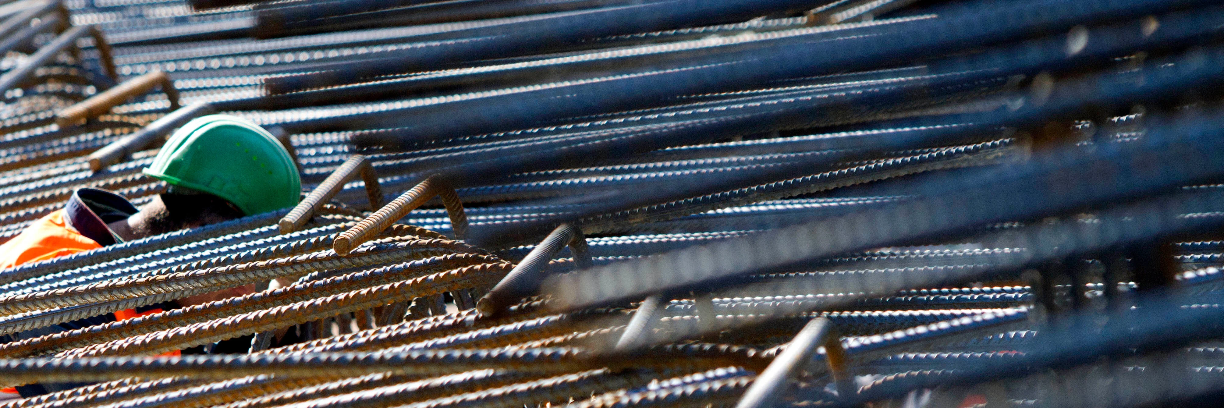 Ein Arbeiter beugt sich inmitten von Stahlträgern für den Neubau der Europäischen Zentralbank (EZB) in Frankfurt am Main zu einem Kollegen hinunter. 