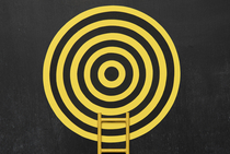 Symbolbild: Dartscheibe mit daran angelehnter Leiter