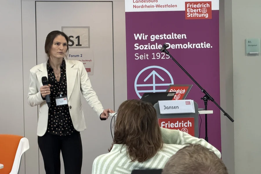 Dr. Anika Jansen stehend hinter einem Rednerpult mit Mikrofon in der Hand.