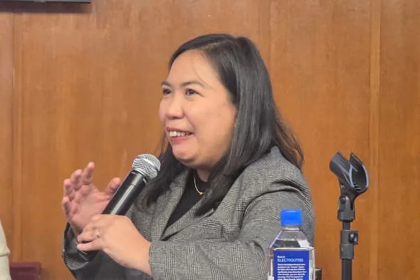 Portrait von Machris Cabreros während sie in ein Mikrofon spricht.