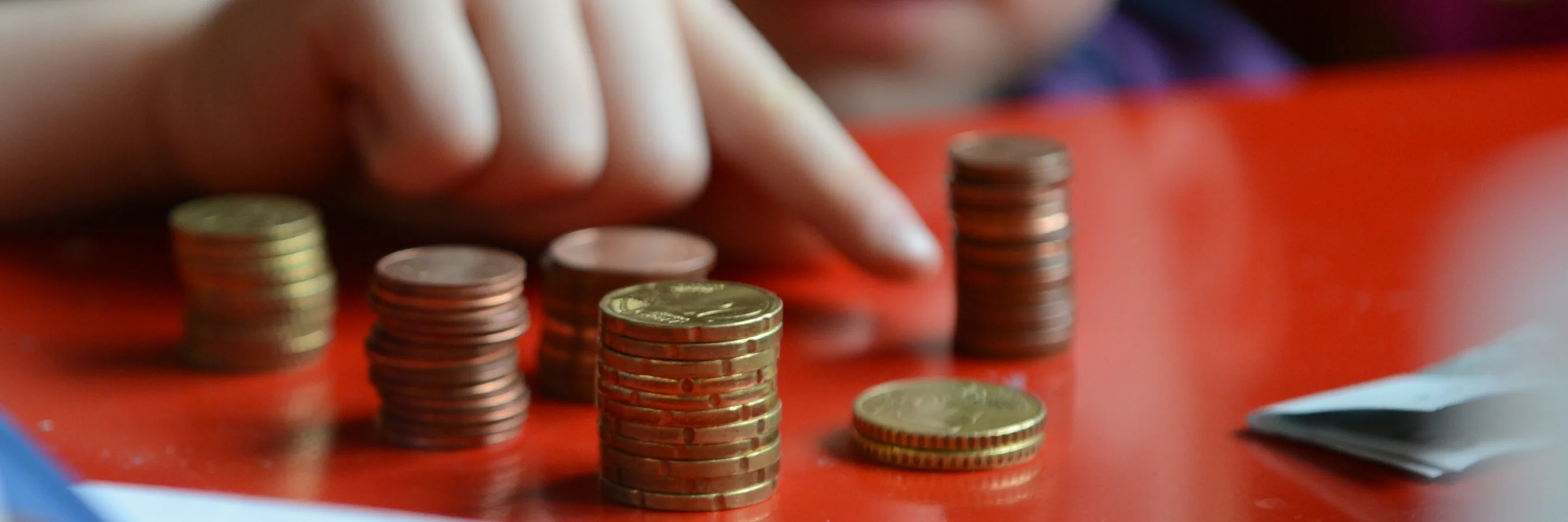 Ein Kind zeigt auf mehrere Stapel von Münzen