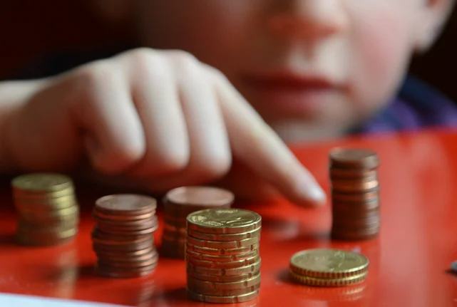 Ein Kind zeigt auf mehrere Stapel von Münzen
