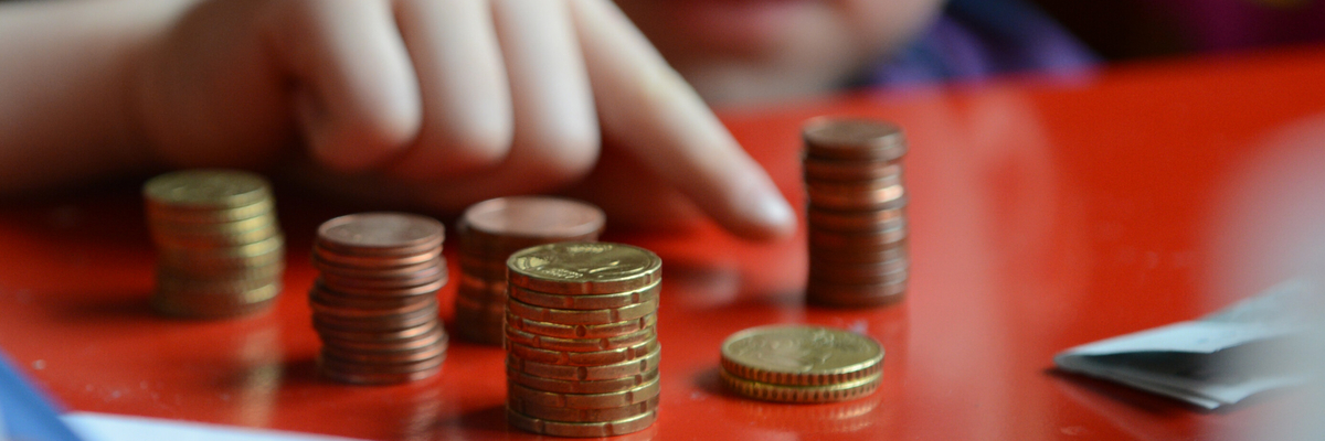 Ein Kind zeigt auf mehrere Stapel von Münzen